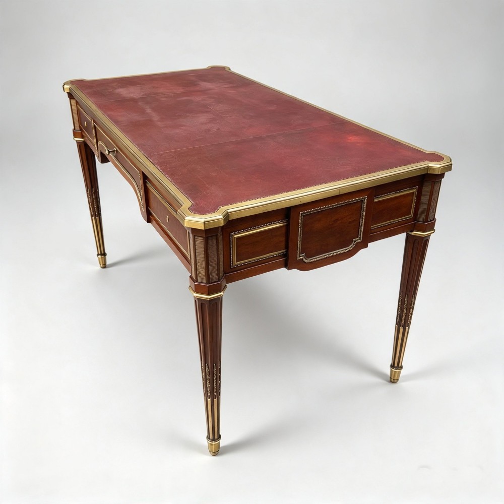 A French Napoleon III style mahogany bureau plat featuring a red leather inset top, gilt bronze mounts, three frieze drawers, and tapered fluted legs. View IX