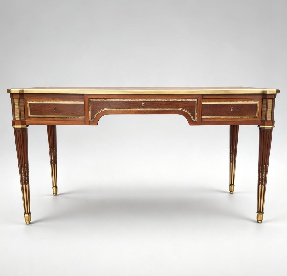 A French Napoleon III style mahogany bureau plat featuring a red leather inset top, gilt bronze mounts, three frieze drawers, and tapered fluted legs. View X