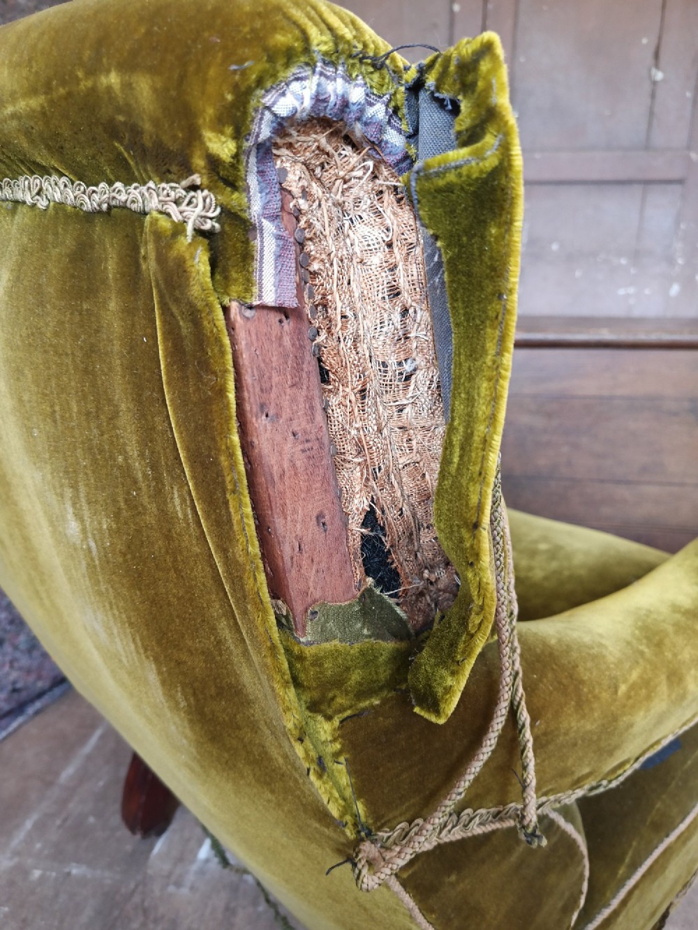 An antique Victorian low easy chair upholstered in olive green velvet with turned wooden arm supports and legs on brass castors. View VI