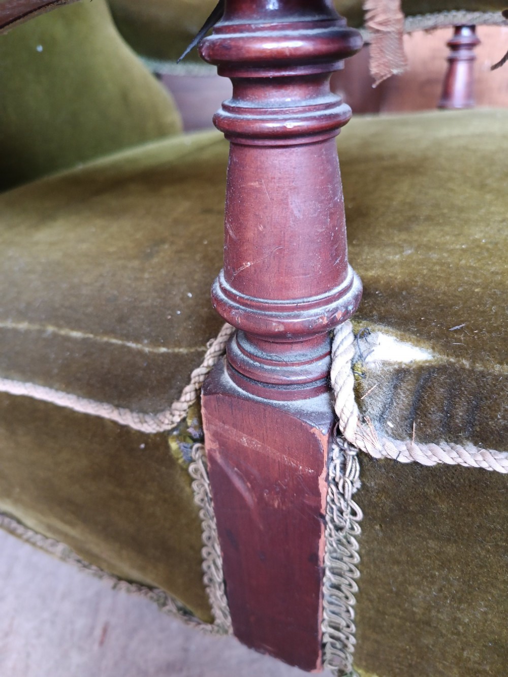 An antique Victorian low easy chair upholstered in olive green velvet with turned wooden arm supports and legs on brass castors. View XII