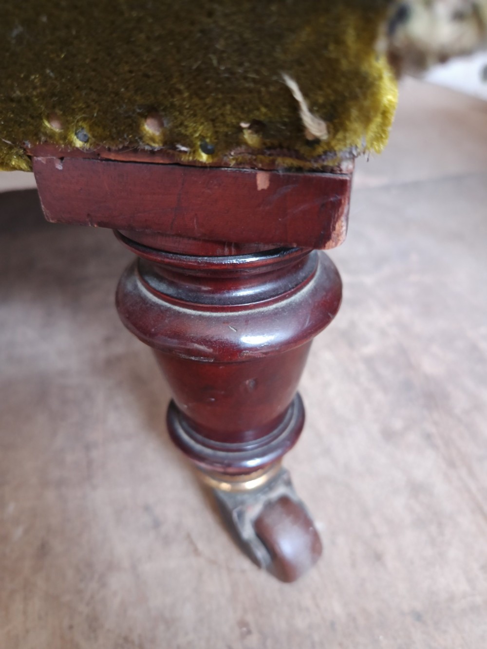 An antique Victorian low easy chair upholstered in olive green velvet with turned wooden arm supports and legs on brass castors. View XIII