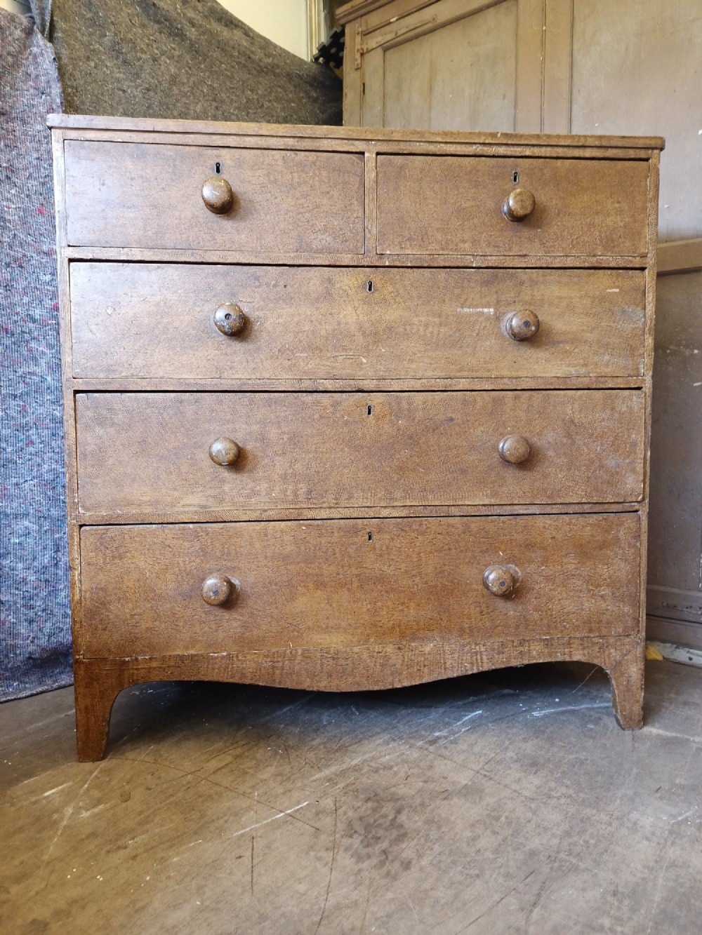 A Regency pine chest of drawers featuring a two-over-three drawer configuration, turned wooden knobs, and a shaped apron bottom.