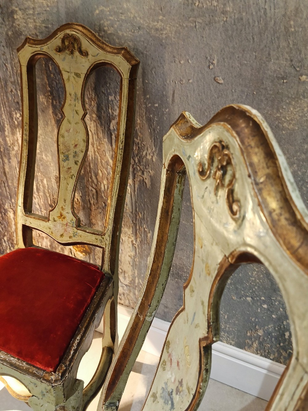 A pair of 18th-century North Italian side chairs featuring distressed cream painted frames with carved crests, cabriole legs, and red velvet seats. View III