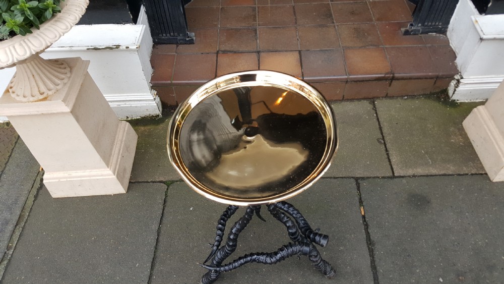 A late 19th-century occasional table featuring a round polished brass tray top mounted on a tripod base constructed from three dark spiralled horns. View II