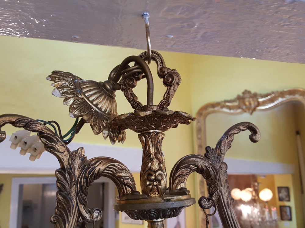 A pair of gilt metal ceiling chandeliers featuring a central figure of a cherub seated on a swing within an ornate lyre-shaped frame with two candle arms. View IV