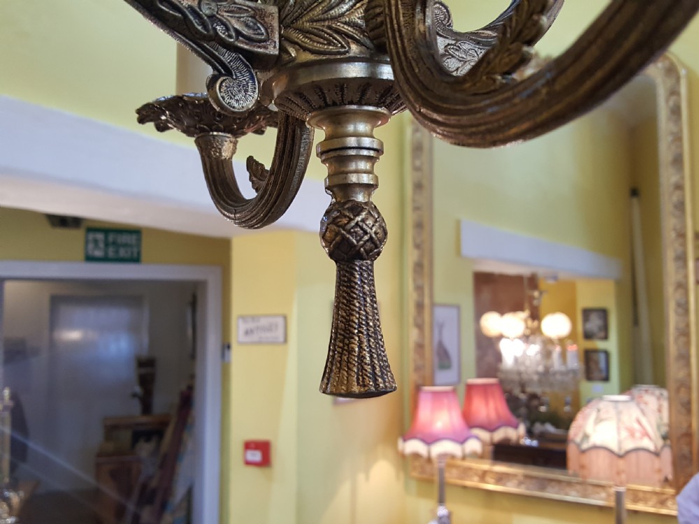 A pair of gilt metal ceiling chandeliers featuring a central figure of a cherub seated on a swing within an ornate lyre-shaped frame with two candle arms. View VI