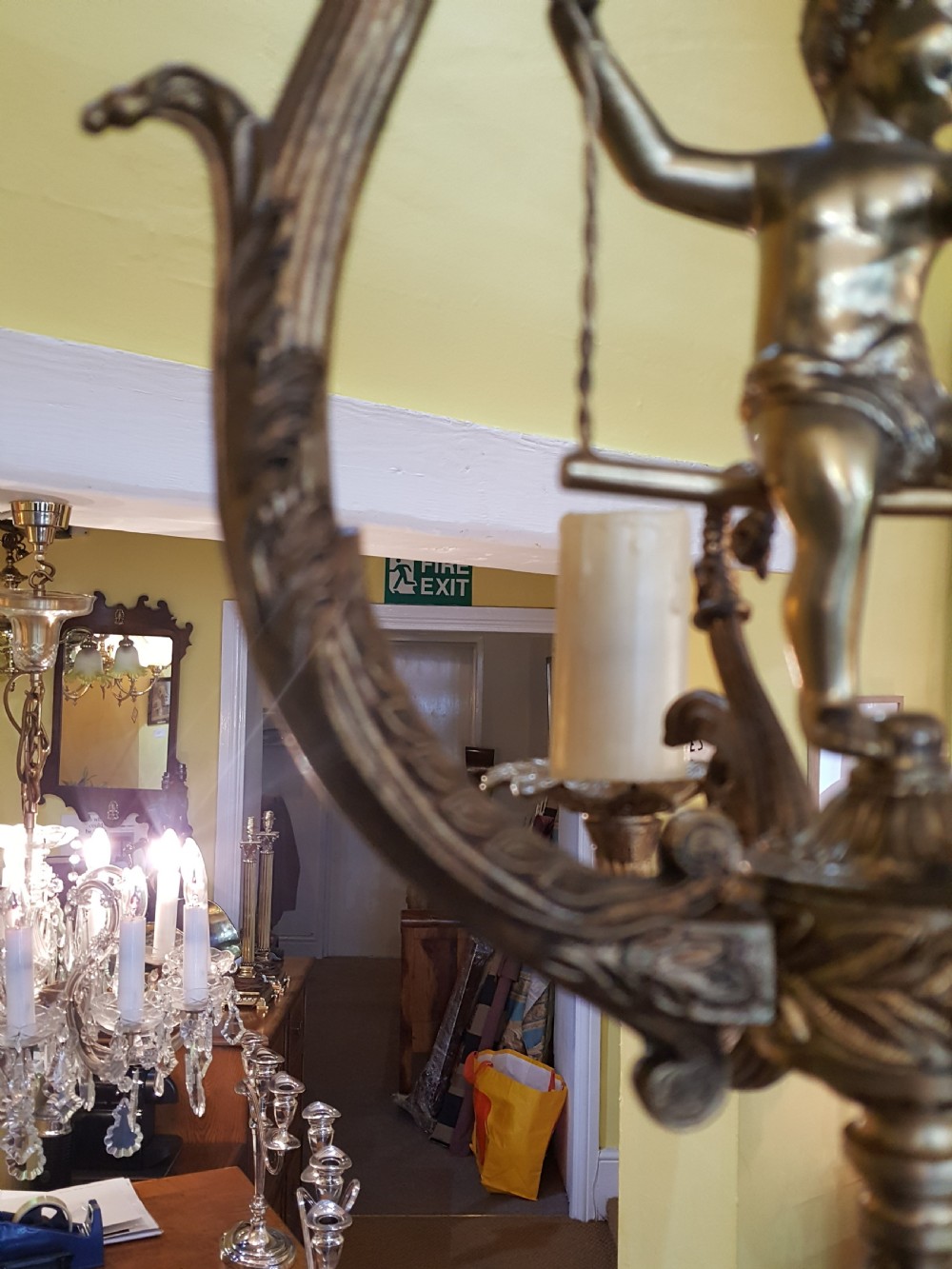 A pair of gilt metal ceiling chandeliers featuring a central figure of a cherub seated on a swing within an ornate lyre-shaped frame with two candle arms. View VII