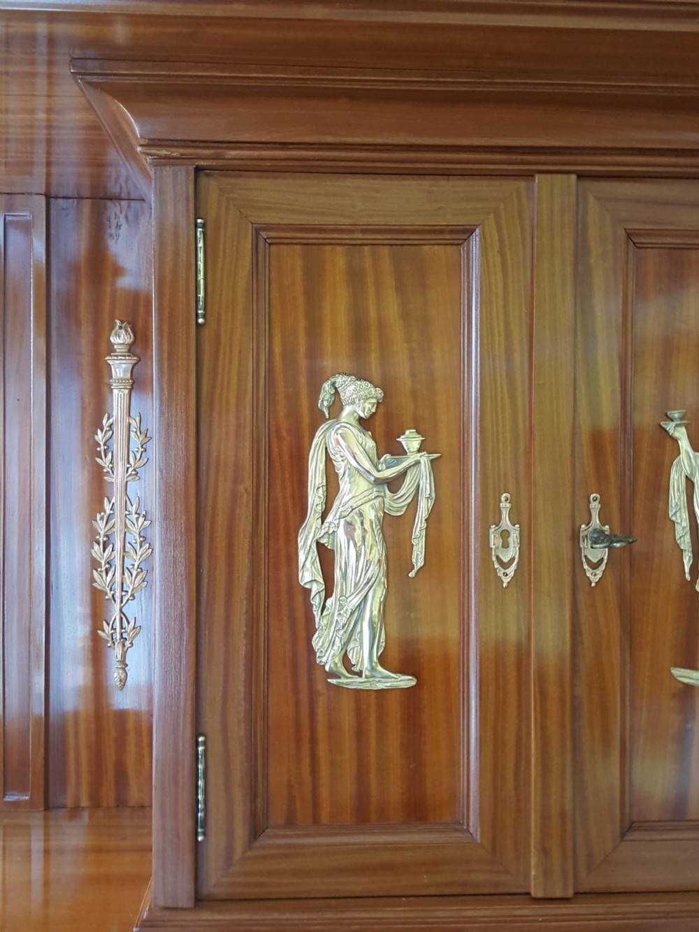 A tall late 19th-century Swiss satinwood salon cabinet featuring a pediment top, gilded metal mounts, glazed display compartments, central mirror, and inlaid door panels. View II