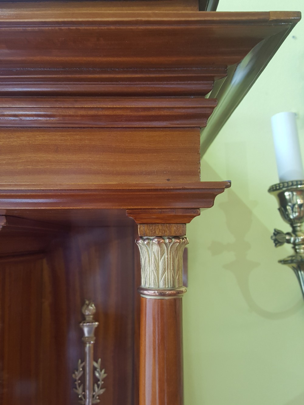 A tall late 19th-century Swiss satinwood salon cabinet featuring a pediment top, gilded metal mounts, glazed display compartments, central mirror, and inlaid door panels. View IX