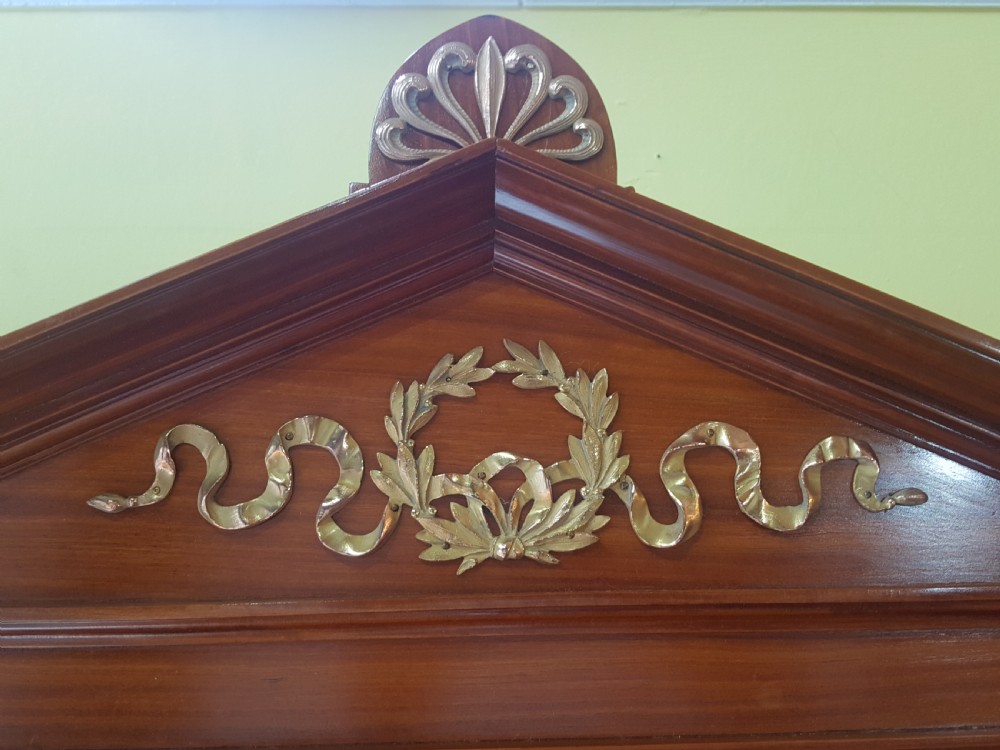 A tall late 19th-century Swiss satinwood salon cabinet featuring a pediment top, gilded metal mounts, glazed display compartments, central mirror, and inlaid door panels. View X