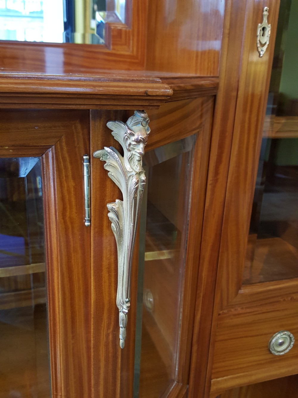 A tall late 19th-century Swiss satinwood salon cabinet featuring a pediment top, gilded metal mounts, glazed display compartments, central mirror, and inlaid door panels. View XI