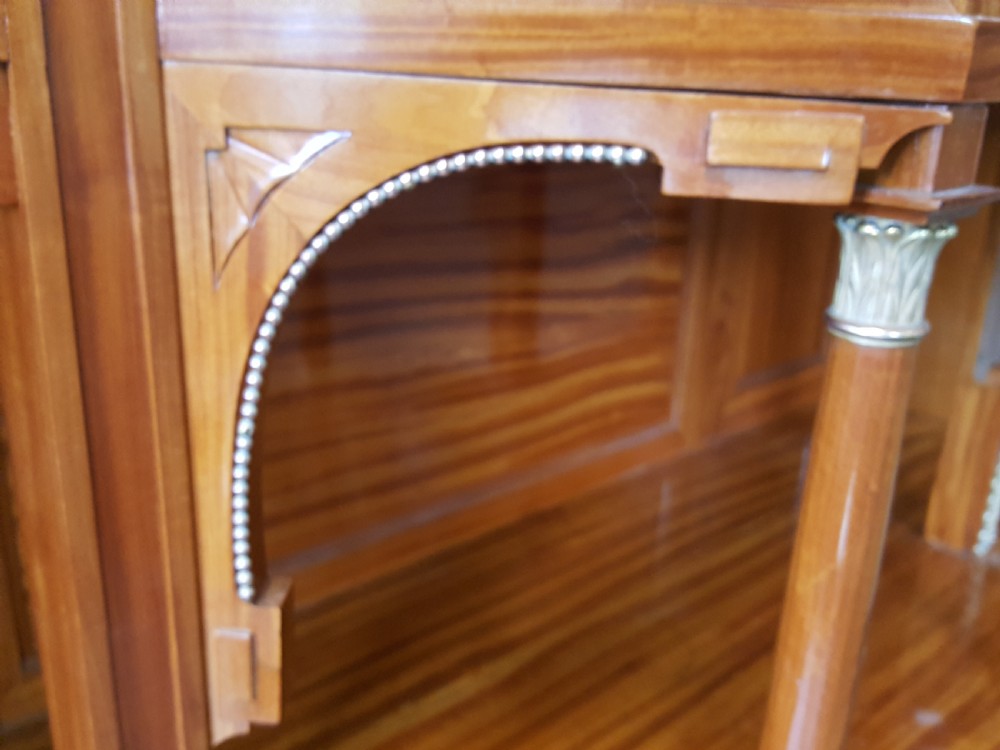 A tall late 19th-century Swiss satinwood salon cabinet featuring a pediment top, gilded metal mounts, glazed display compartments, central mirror, and inlaid door panels. View XIV