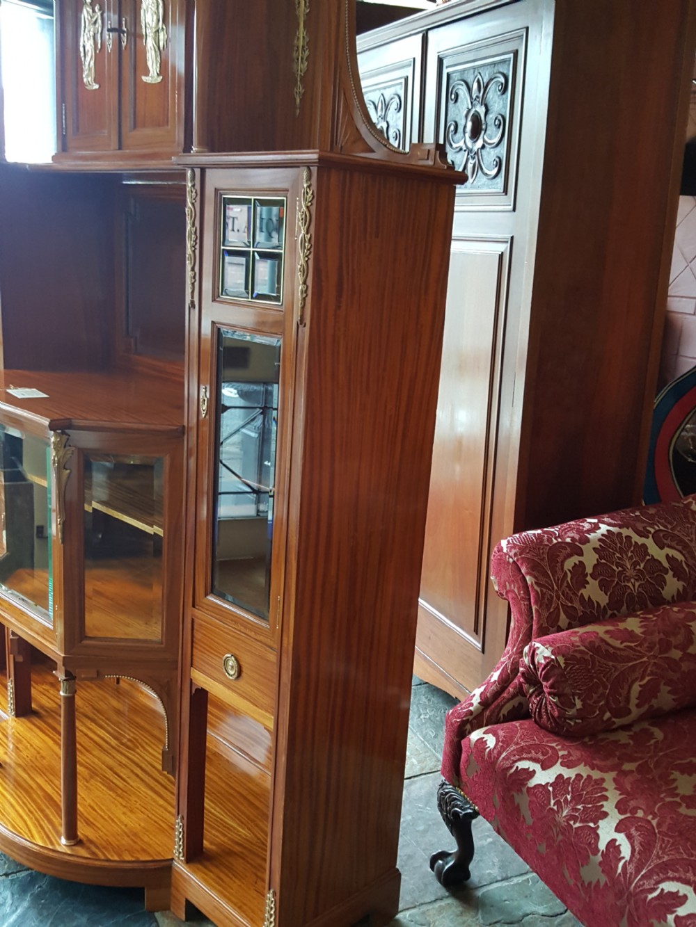 A tall late 19th-century Swiss satinwood salon cabinet featuring a pediment top, gilded metal mounts, glazed display compartments, central mirror, and inlaid door panels. View XVIII