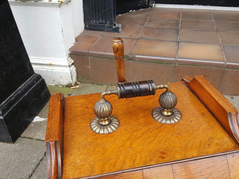 A late Victorian solid oak coal scuttle featuring a slanted panelled front, brass top carrying handle, and rear wooden shovel. View II