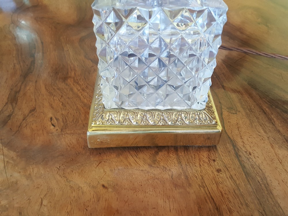 A cut glass urn-form table lamp with ornate gilt metal handles and base, topped with a black and gold patterned domed shade featuring long black fringe trim. View II