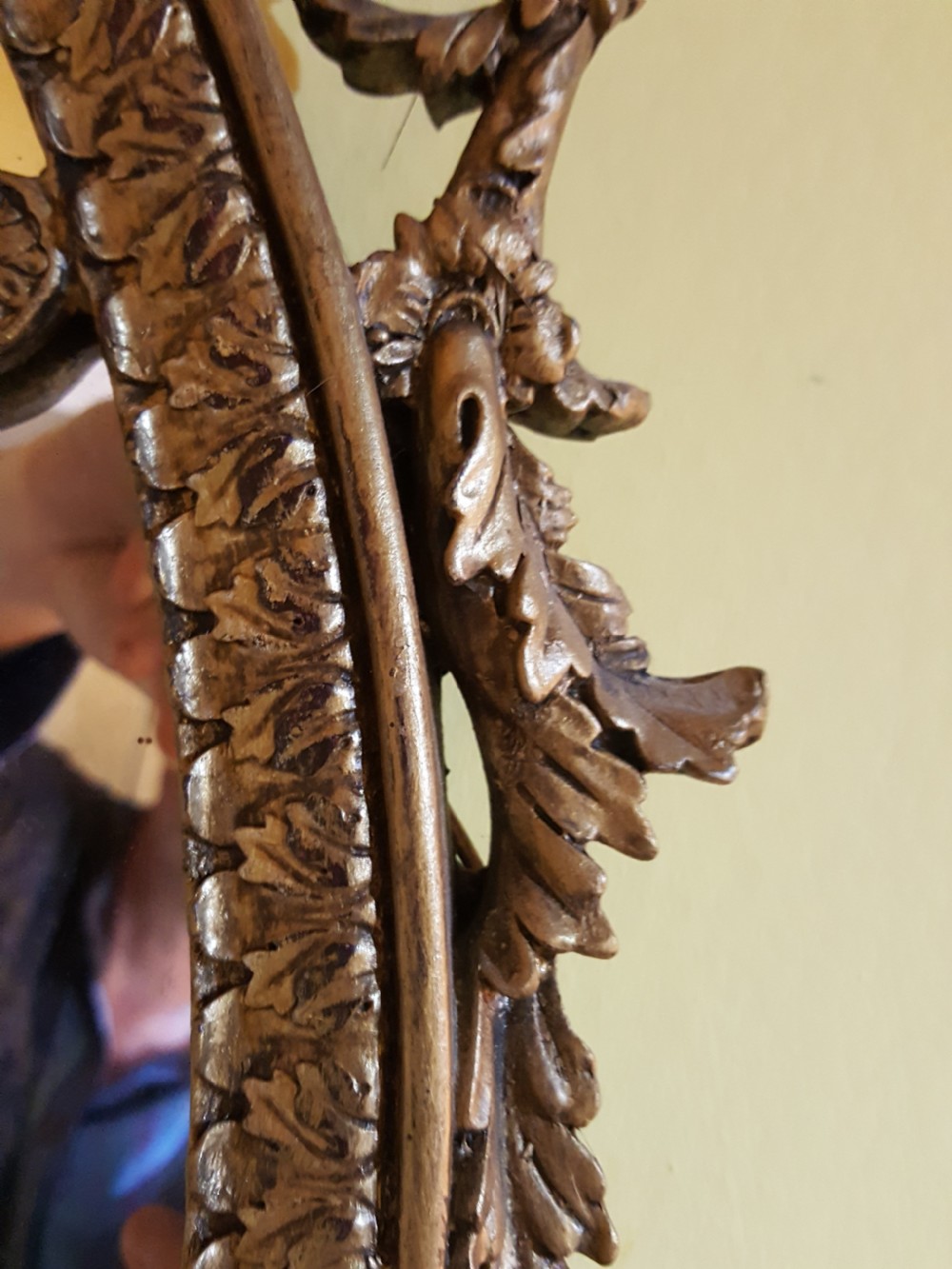 An ornate oval giltwood girandole mirror featuring carved acanthus cresting, ribbon detailing, and two candle sconces at the base. View VII