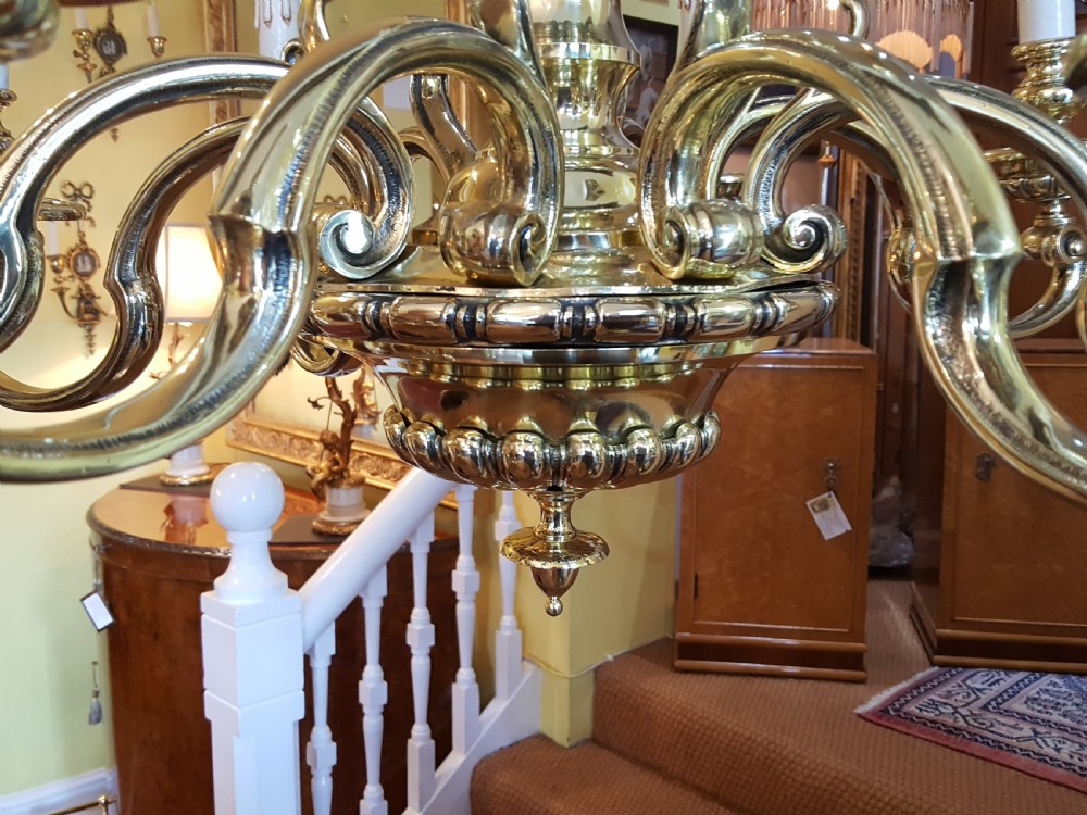 An early twentieth-century brass chandelier featuring eight S-scroll arms surrounding a turned central baluster stem with candle sleeves. View III