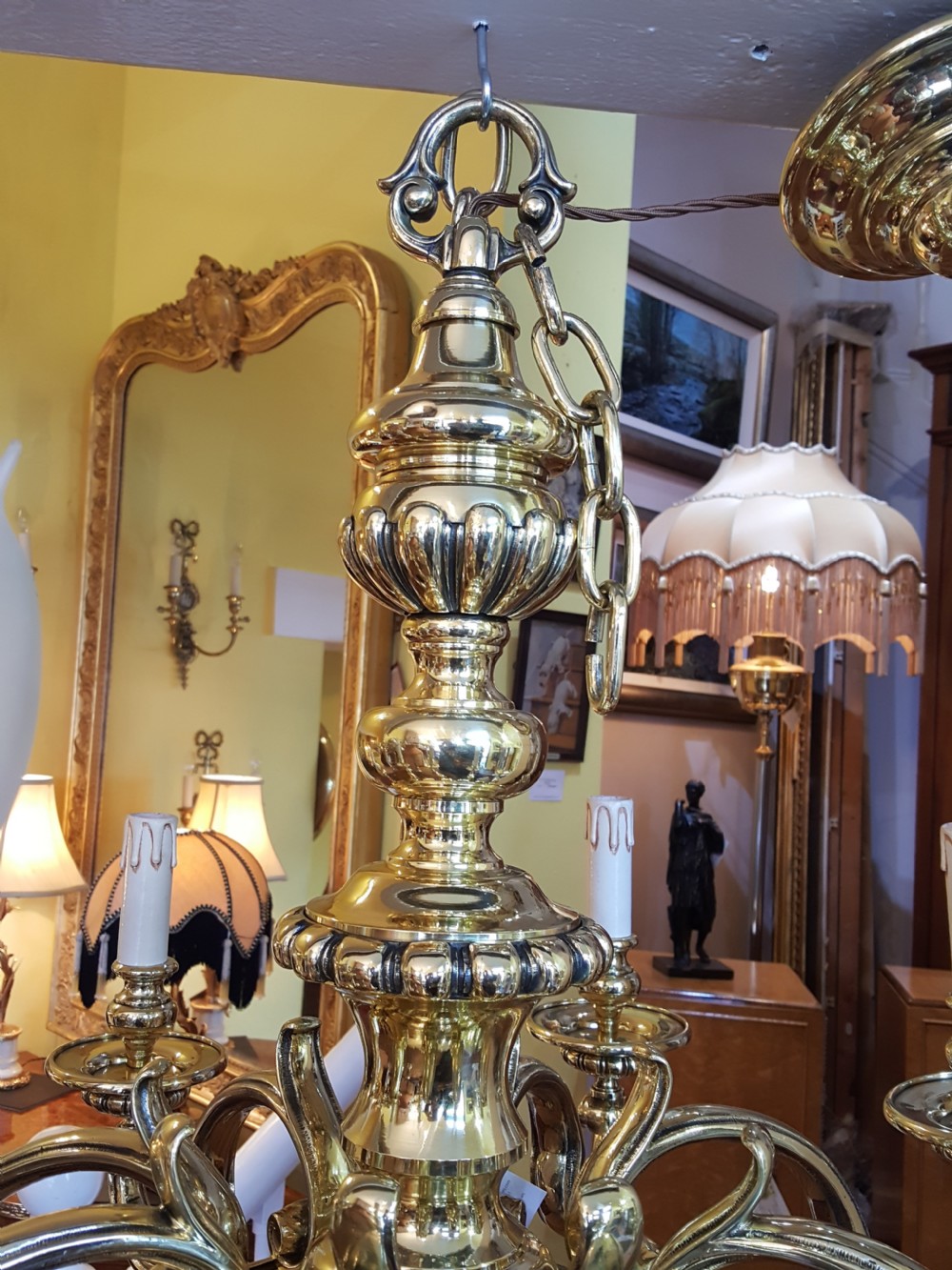 An early twentieth-century brass chandelier featuring eight S-scroll arms surrounding a turned central baluster stem with candle sleeves. View VI
