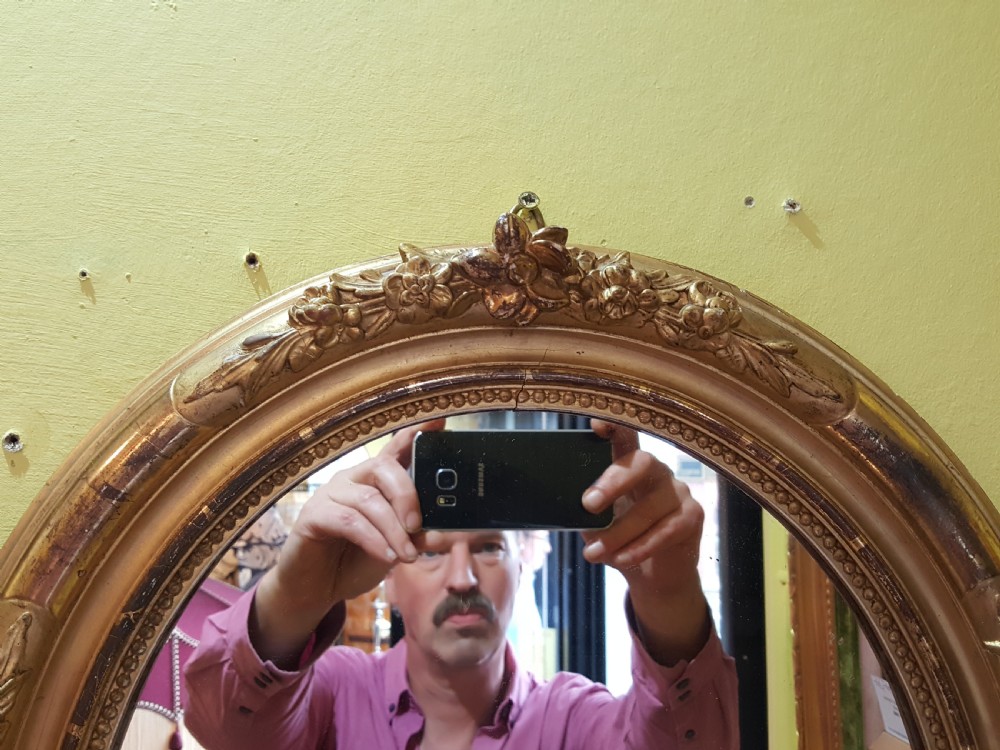 A pair of matching oval wall mirrors housed in carved giltwood frames decorated with floral motifs and beaded borders. View IV