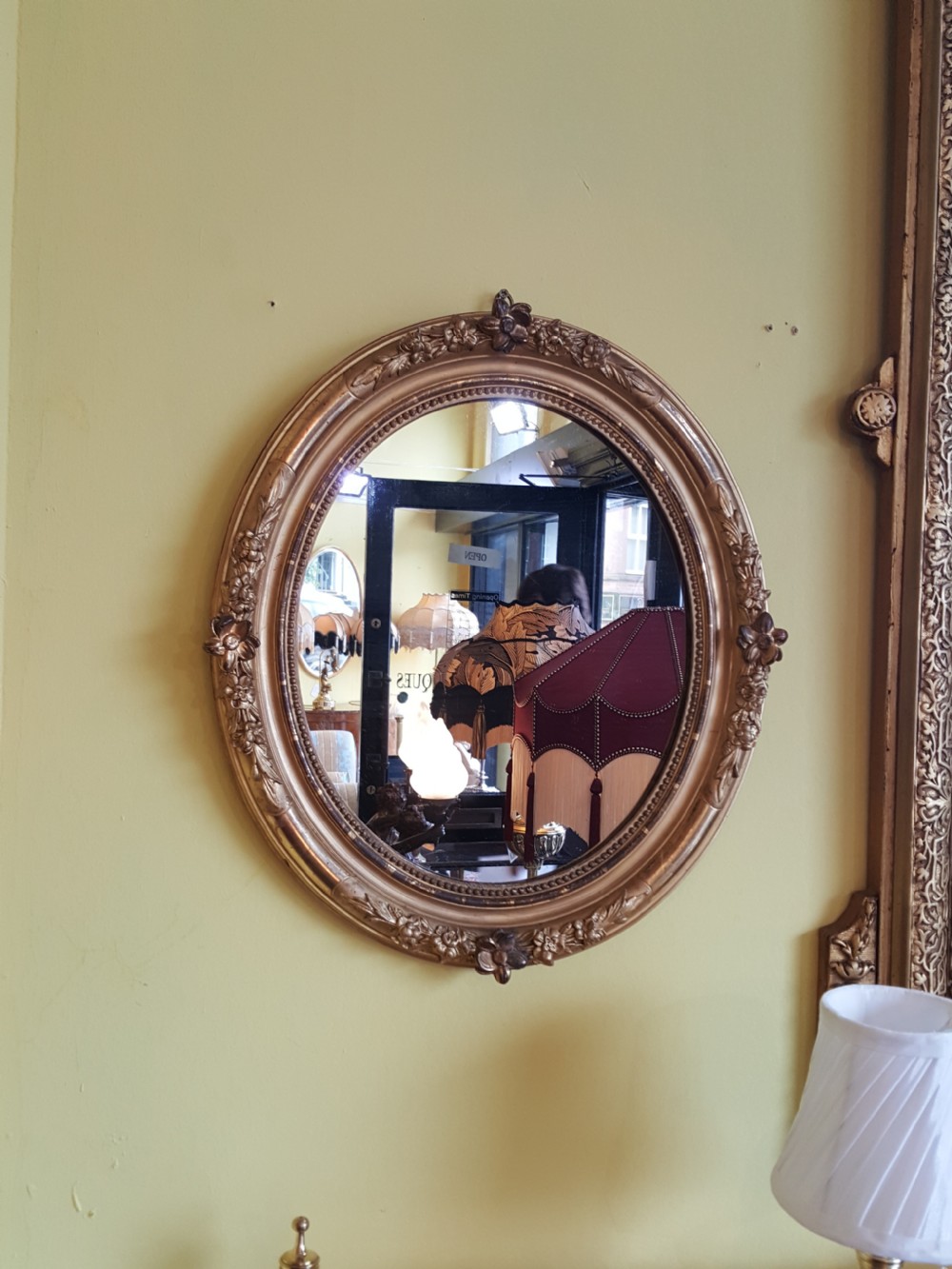 A pair of matching oval wall mirrors housed in carved giltwood frames decorated with floral motifs and beaded borders. View VI