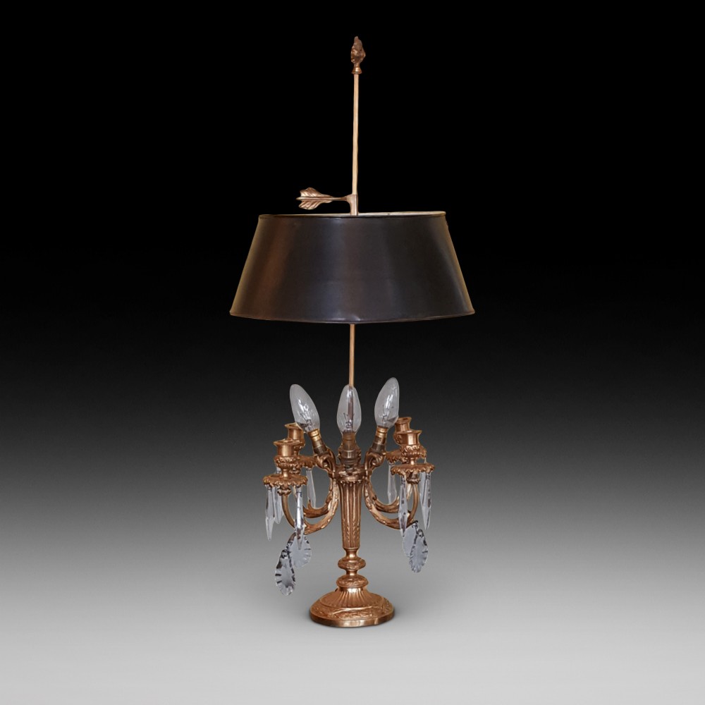 An early 20th-century French gilt bronze four-branch candelabrum converted into a table lamp, featuring hanging crystal drops, a central brass rod, and a black shade.