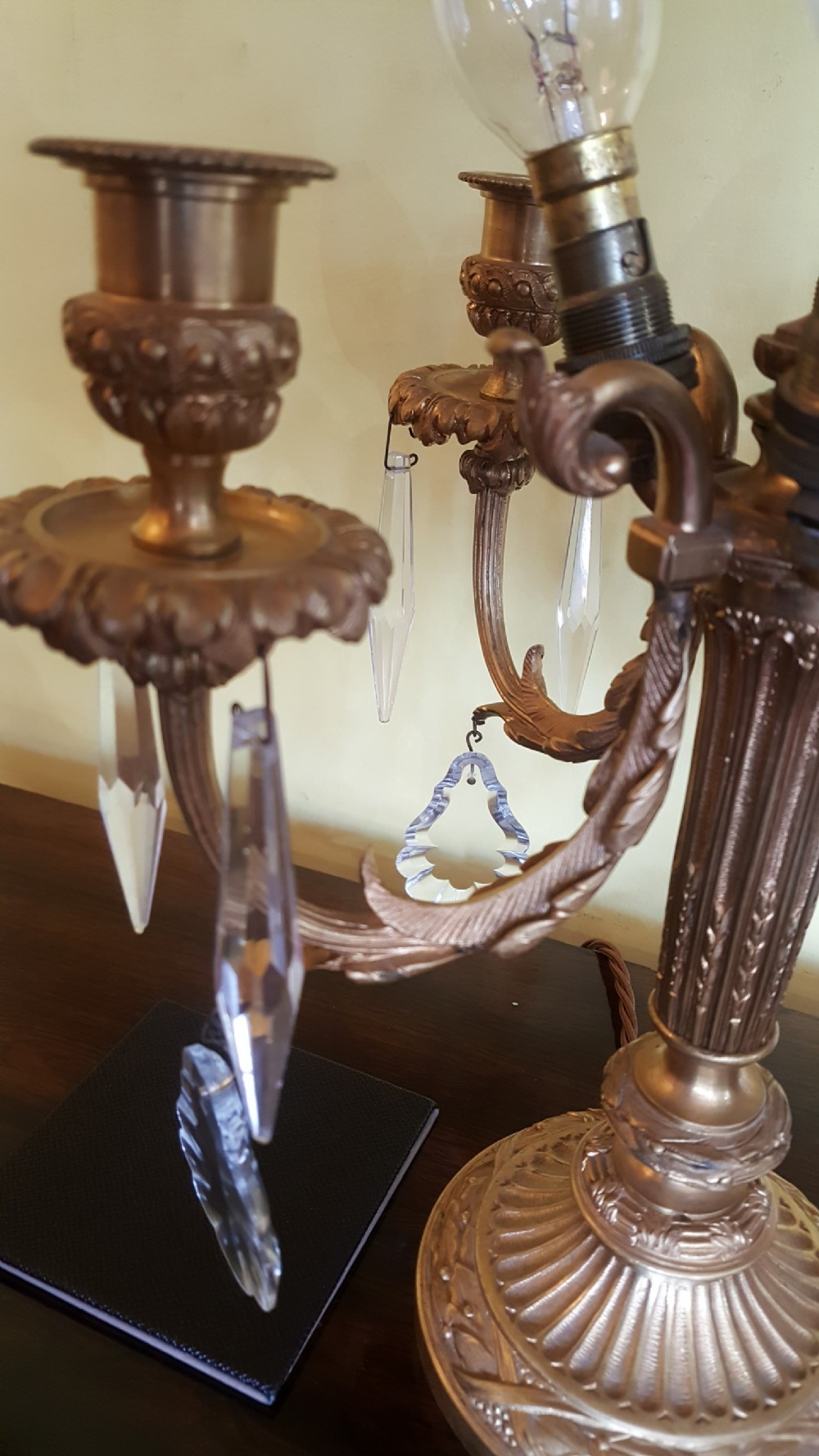 An early 20th-century French gilt bronze four-branch candelabrum converted into a table lamp, featuring hanging crystal drops, a central brass rod, and a black shade. View V