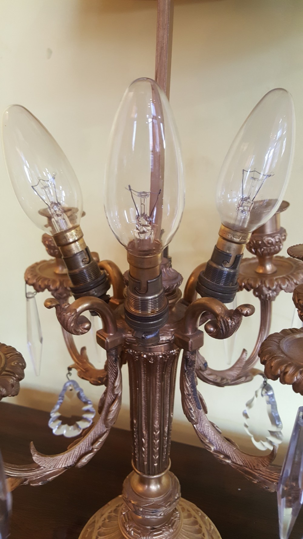 An early 20th-century French gilt bronze four-branch candelabrum converted into a table lamp, featuring hanging crystal drops, a central brass rod, and a black shade. View VI