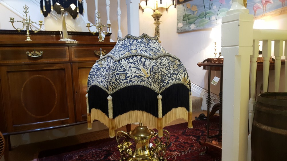 An Art Nouveau brass table lamp shaped like an urn with foliate handles and an intricate patterned fabric shade with decorative fringe. View II
