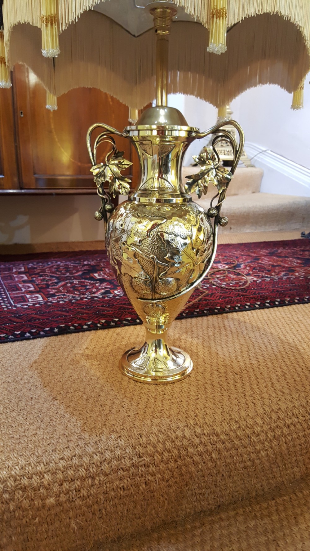 An Art Nouveau brass table lamp shaped like an urn with foliate handles and an intricate patterned fabric shade with decorative fringe. View III