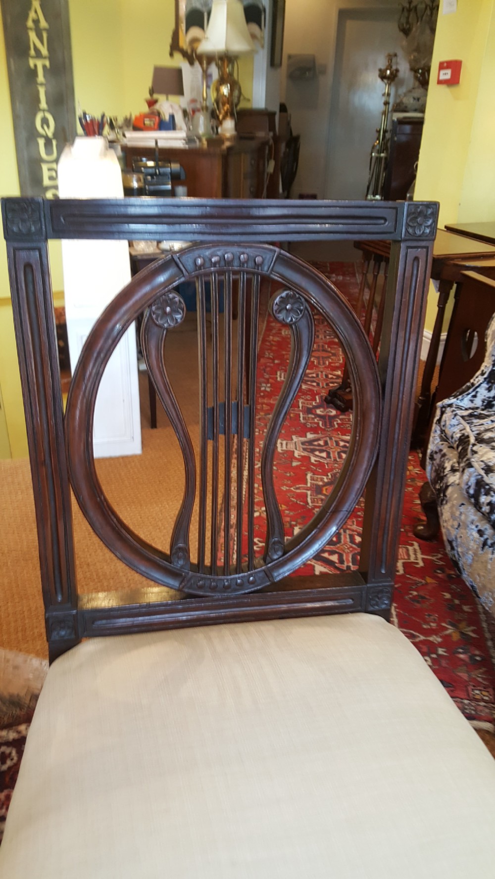 A set of four Regency mahogany side chairs featuring carved lyre back splats inside circular frame apertures, with off-white upholstered seats and fluted front legs. View II