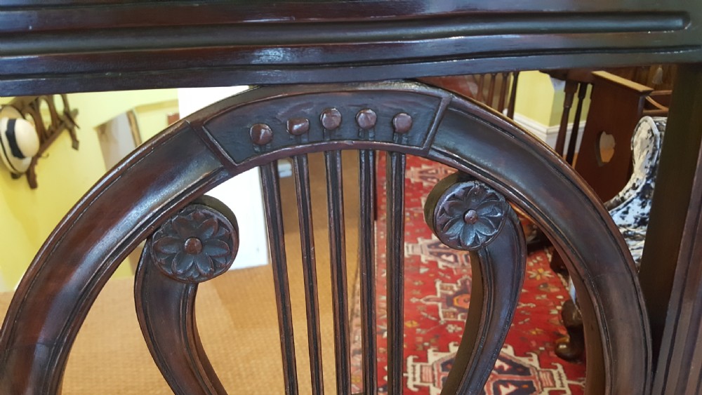 A set of four Regency mahogany side chairs featuring carved lyre back splats inside circular frame apertures, with off-white upholstered seats and fluted front legs. View IV