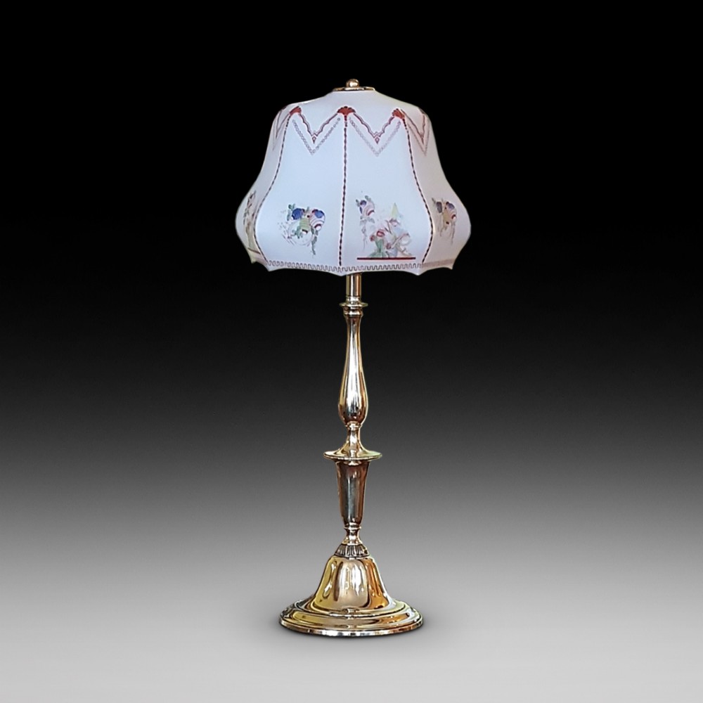 An early twentieth-century polished brass table lamp featuring a contoured stem and a white scalloped fabric shade with embroidered details.