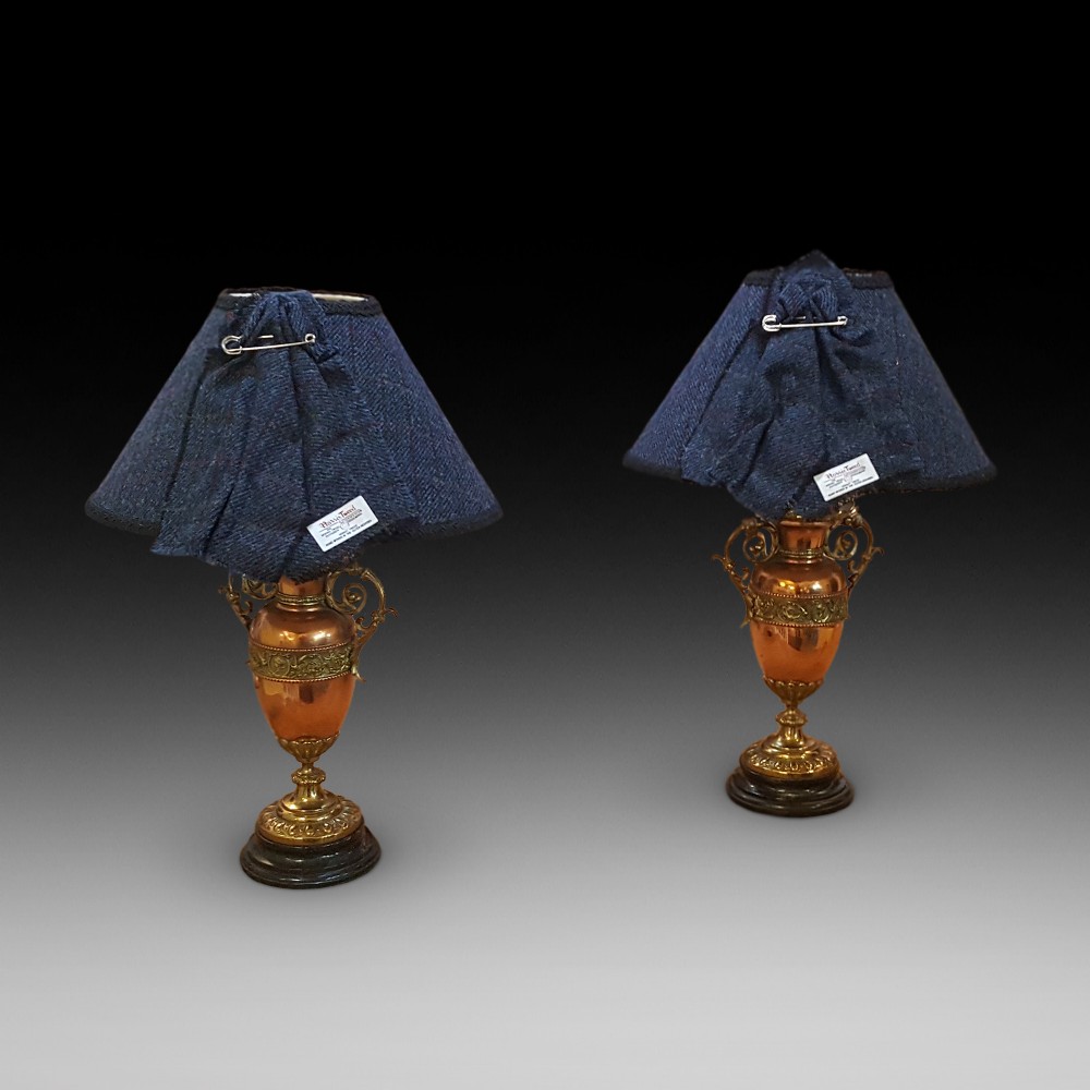 A pair of late 19th-century table lamps with urn-shaped copper and brass bases paired with blue tweed shades.