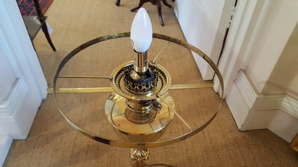 A Victorian brass oil lamp featuring a decorative cast base, fluted stem, central brass reservoir, and a white glass shade. View VI