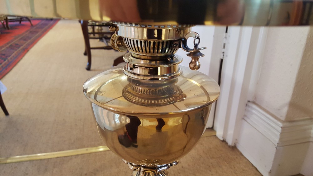 A Victorian brass oil lamp featuring a decorative cast base, fluted stem, central brass reservoir, and a white glass shade. View VII