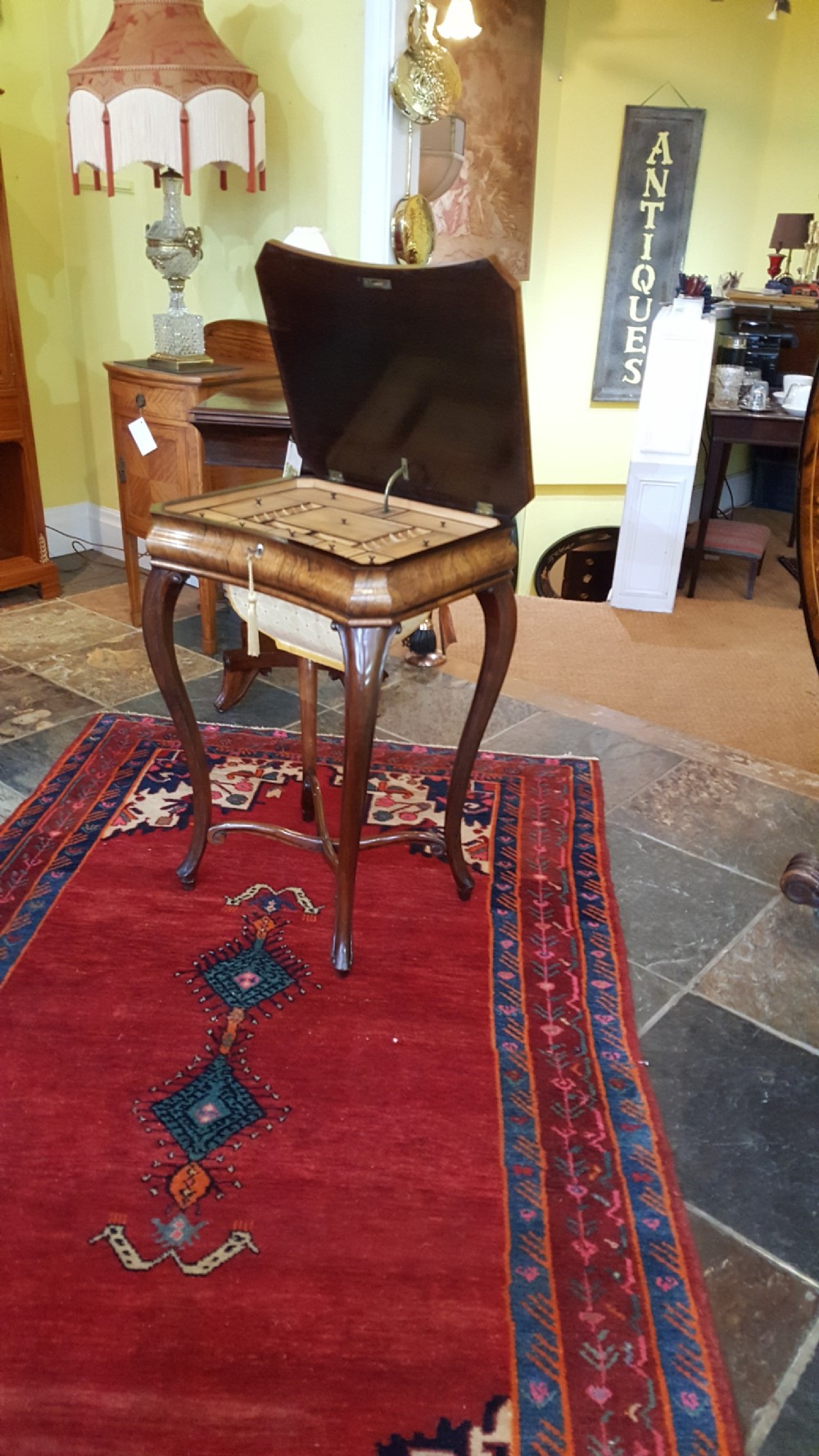 A mid-19th-century dark rosewood sewing table featuring curved cabriole legs, an X-shaped stretcher, and a fabric-covered storage basket underneath. View III