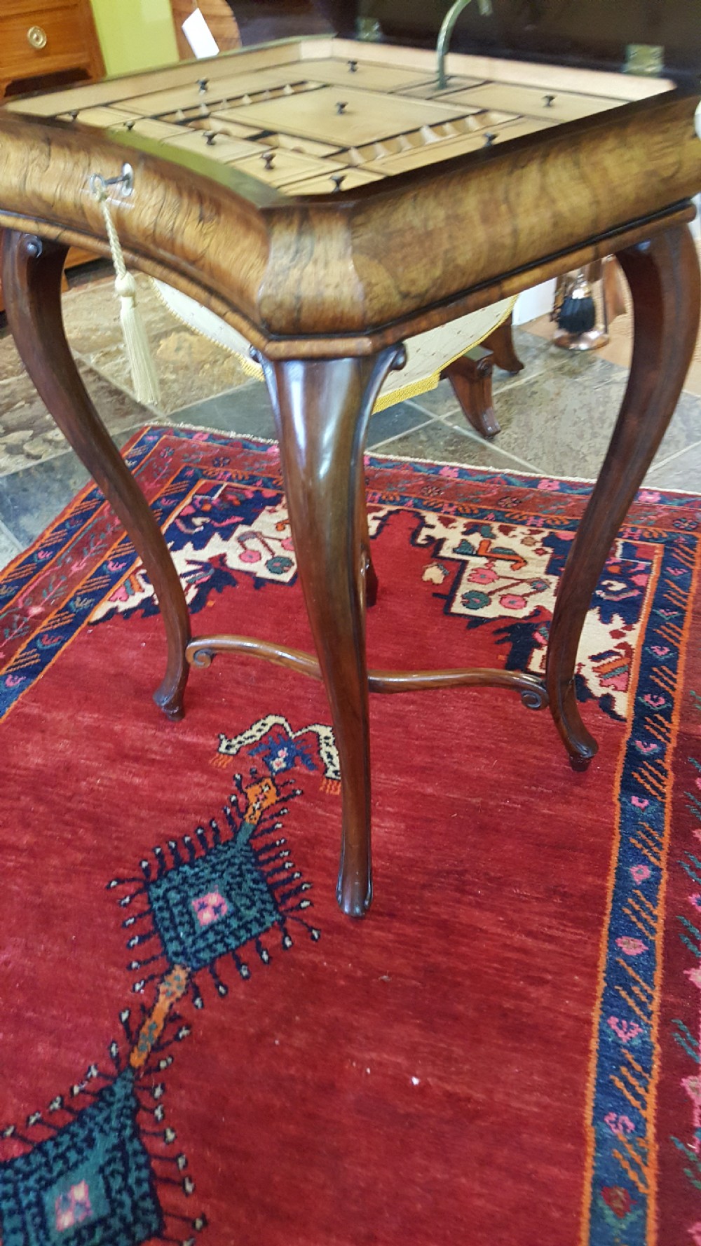 A mid-19th-century dark rosewood sewing table featuring curved cabriole legs, an X-shaped stretcher, and a fabric-covered storage basket underneath. View V