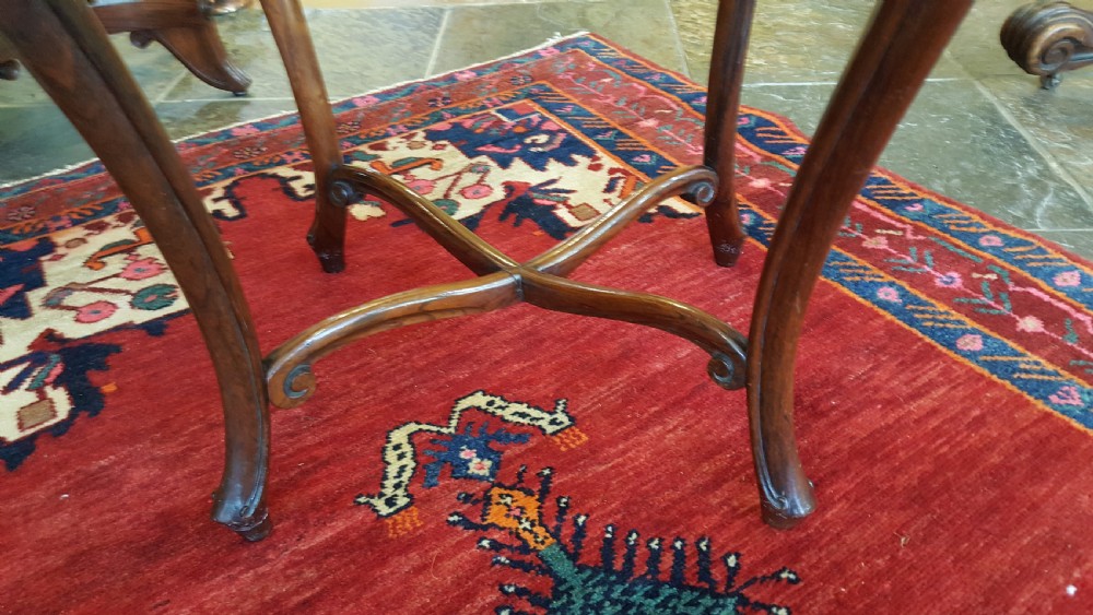 A mid-19th-century dark rosewood sewing table featuring curved cabriole legs, an X-shaped stretcher, and a fabric-covered storage basket underneath. View VI
