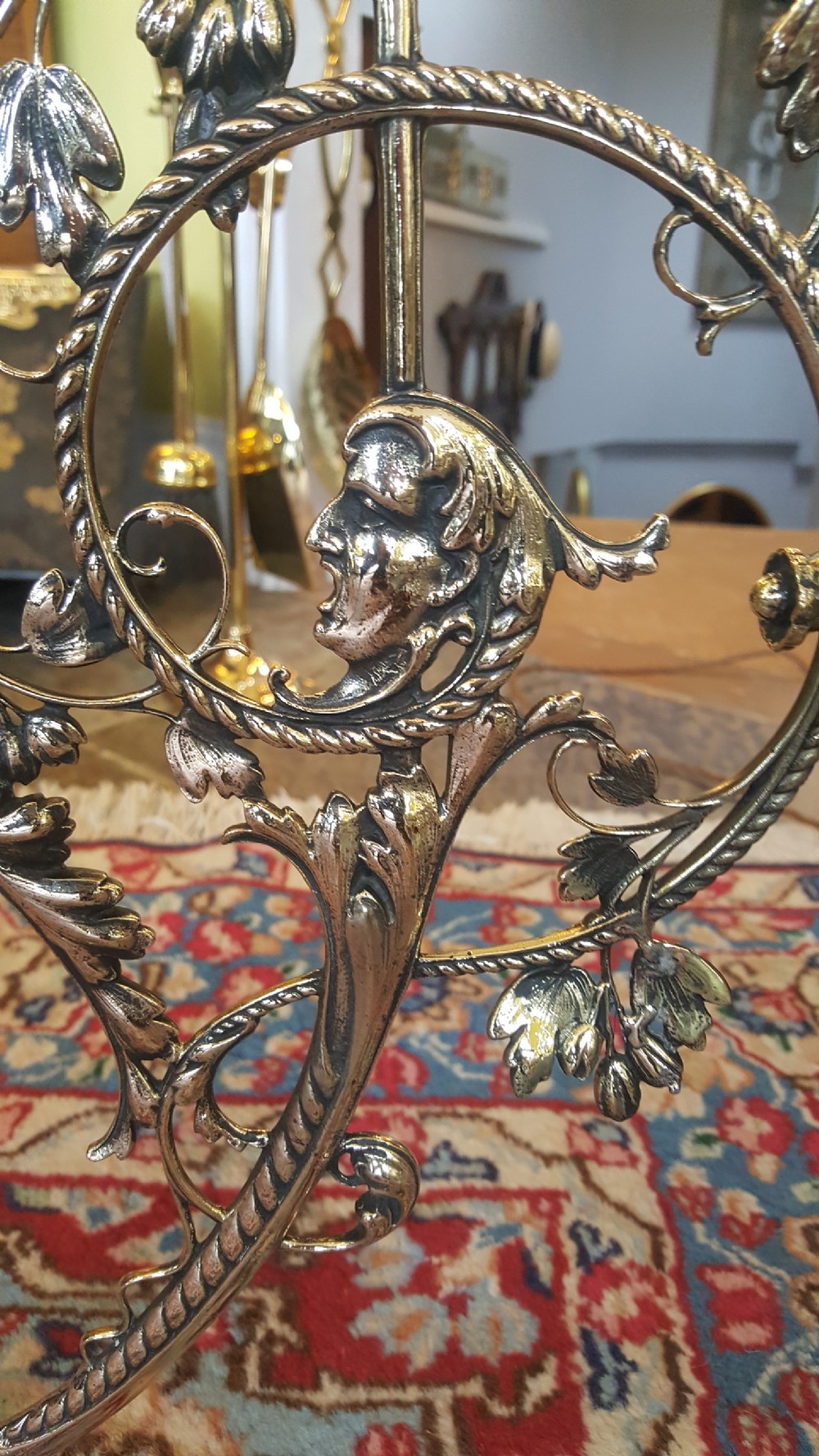 An early 20th-century brass standard lamp featuring an ornate scrollwork tripod base and a botanical patterned domed shade with cream textile fringing. View III