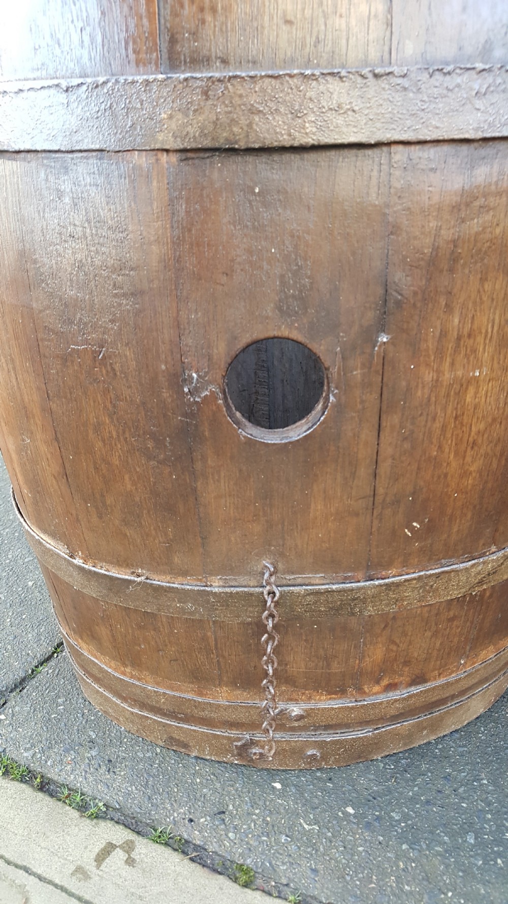An early twentieth-century coopered oak barrel bound with dark iron hoops and featuring a central bung hole. View II