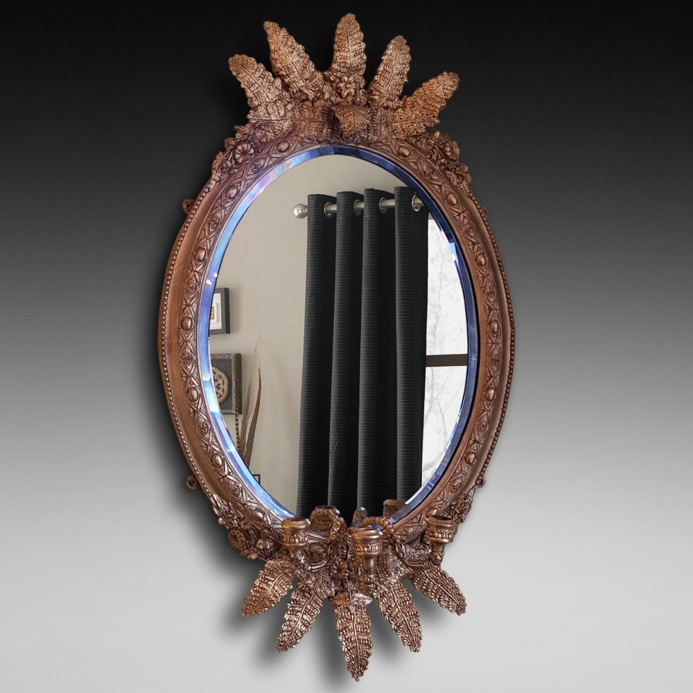 An oval Victorian giltwood wall mirror featuring prominent botanical leaf cresting and integrated candle sconces at the base.