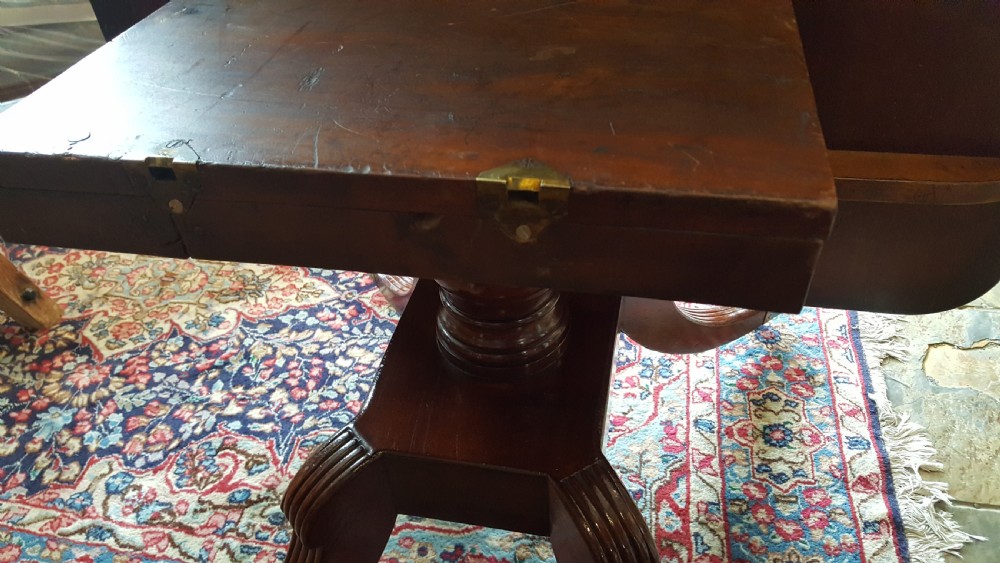 A Regency period rectangular mahogany tilt-top table with crossbanded edges supported by a central turned column and four reeded splayed legs on brass castors. View XI