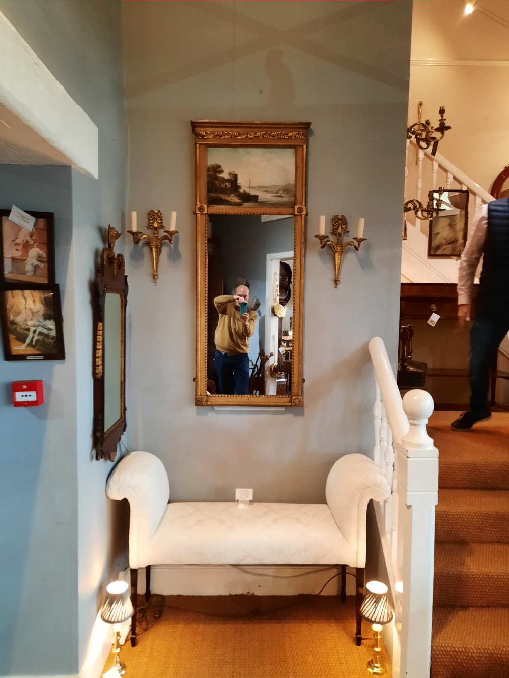 A tall 19th-century gilded composition trumeau mirror featuring an oil landscape painting set within the upper panel and a rectangular mirror plate below. View V