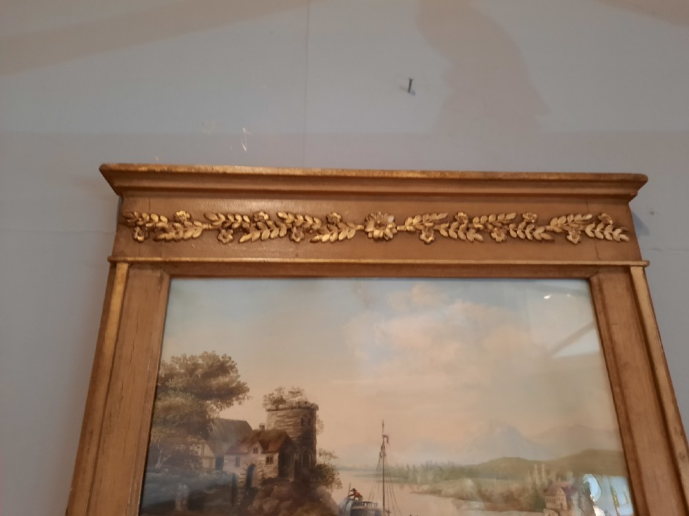 A tall 19th-century gilded composition trumeau mirror featuring an oil landscape painting set within the upper panel and a rectangular mirror plate below. View VI