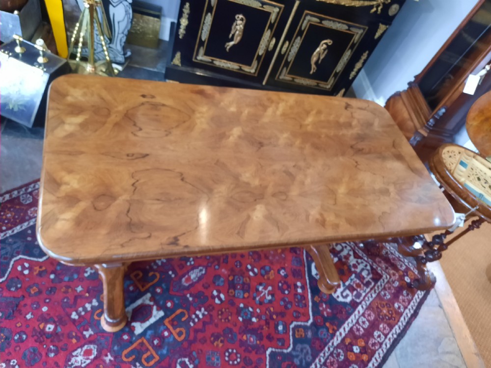 A Late Regency rosewood library table featuring a polished rectangular top with rounded corners, supported by dual faceted end supports resting on stepped plinth bases. View II