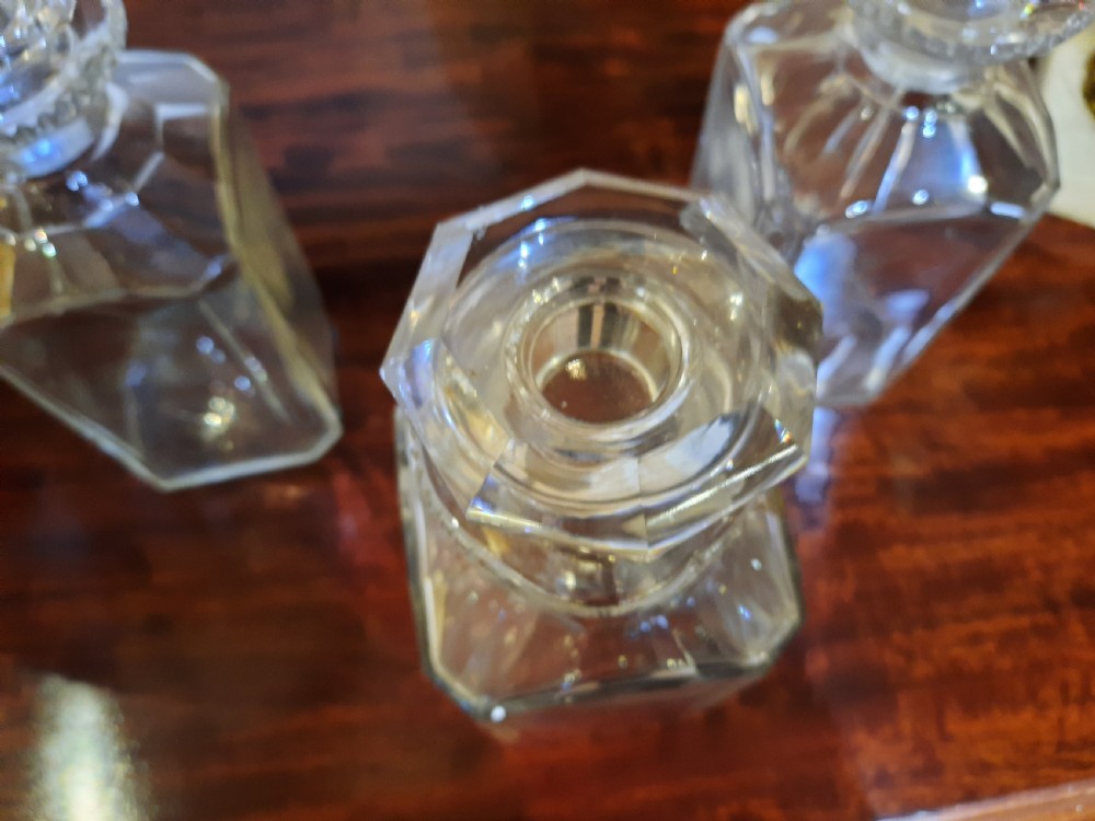 A set of three clear cut glass decanters from the William IV period featuring square bodies and faceted glass stoppers. View II