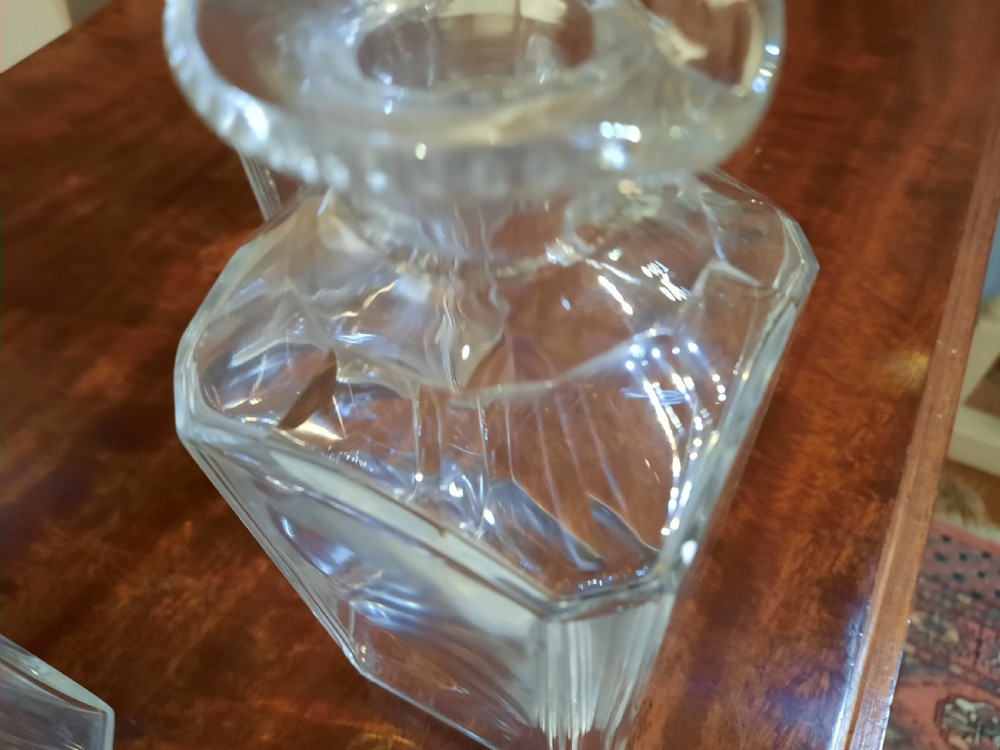 A set of three clear cut glass decanters from the William IV period featuring square bodies and faceted glass stoppers. View IV