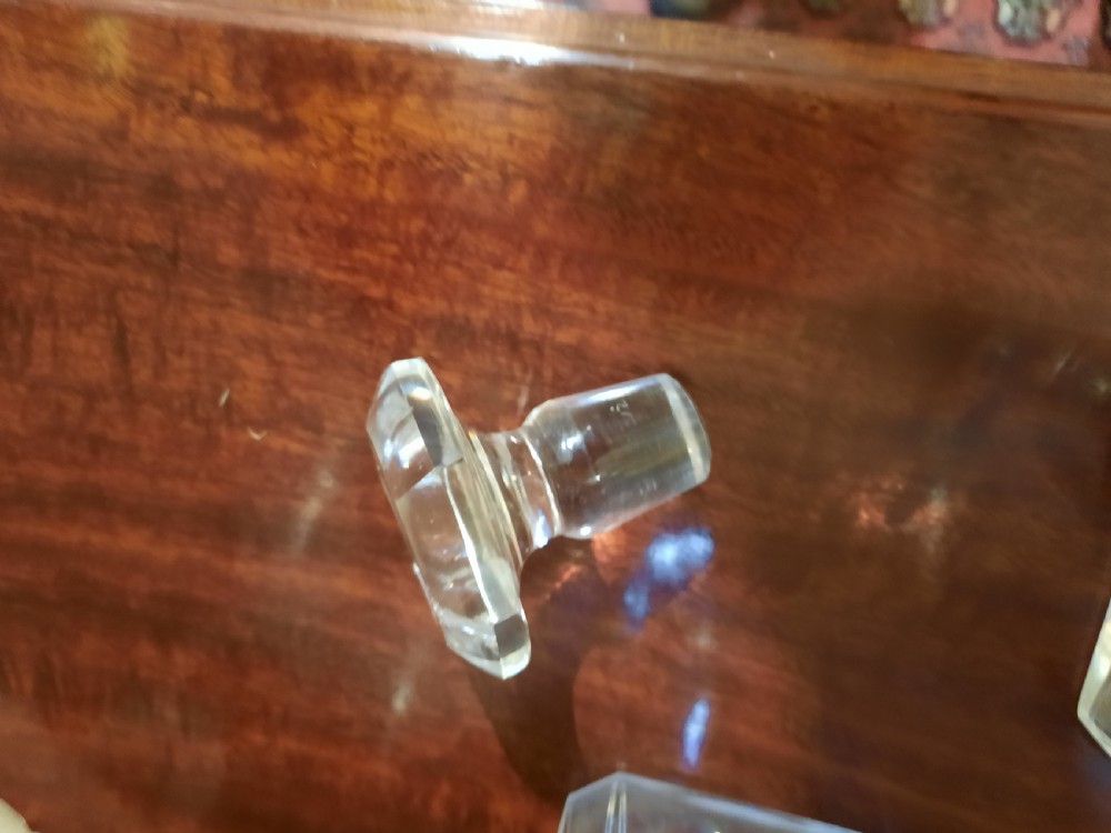 A set of three clear cut glass decanters from the William IV period featuring square bodies and faceted glass stoppers. View V