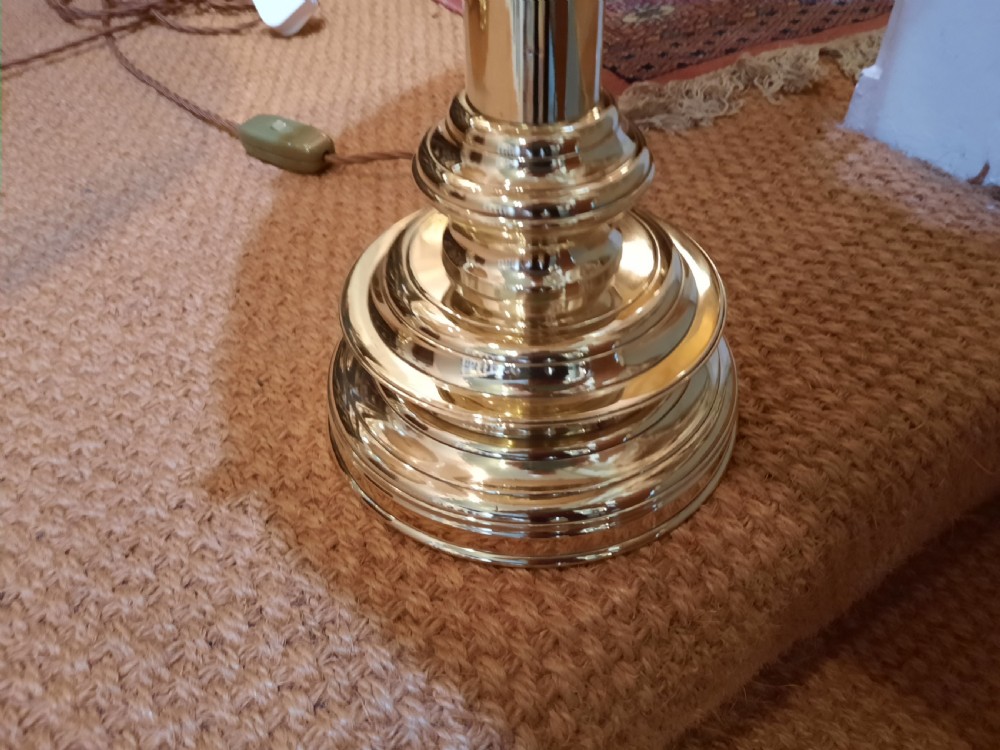 A pair of tall turned brass candlesticks fitted with dome-shaped beige fabric shades featuring scalloped fringe detail. View II
