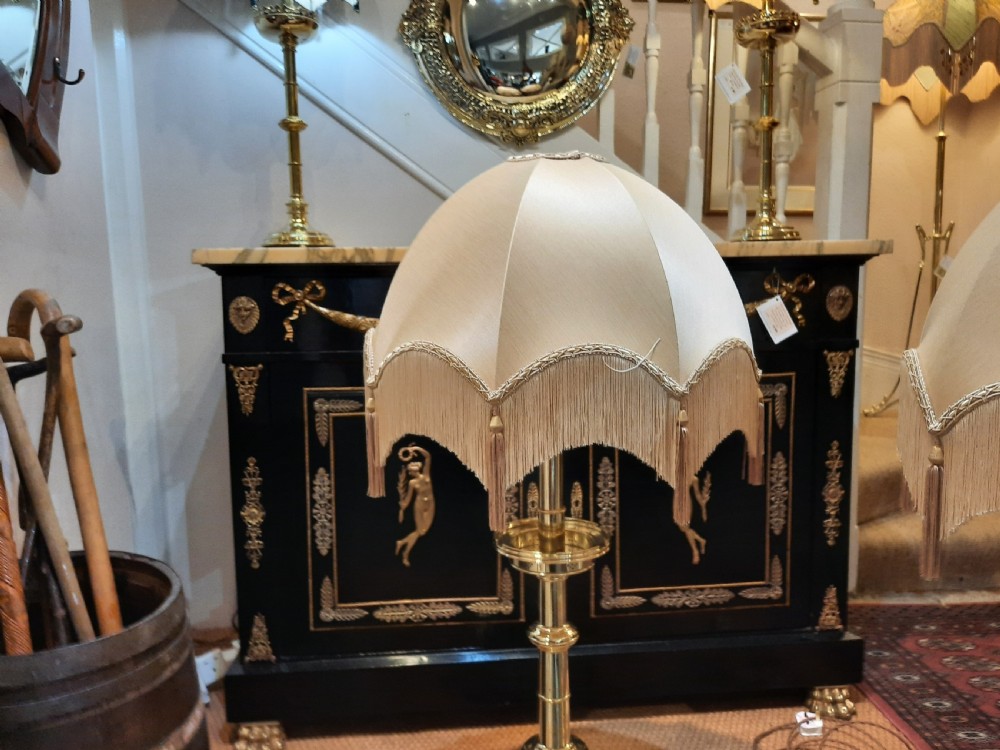 A pair of tall turned brass candlesticks fitted with dome-shaped beige fabric shades featuring scalloped fringe detail. View V